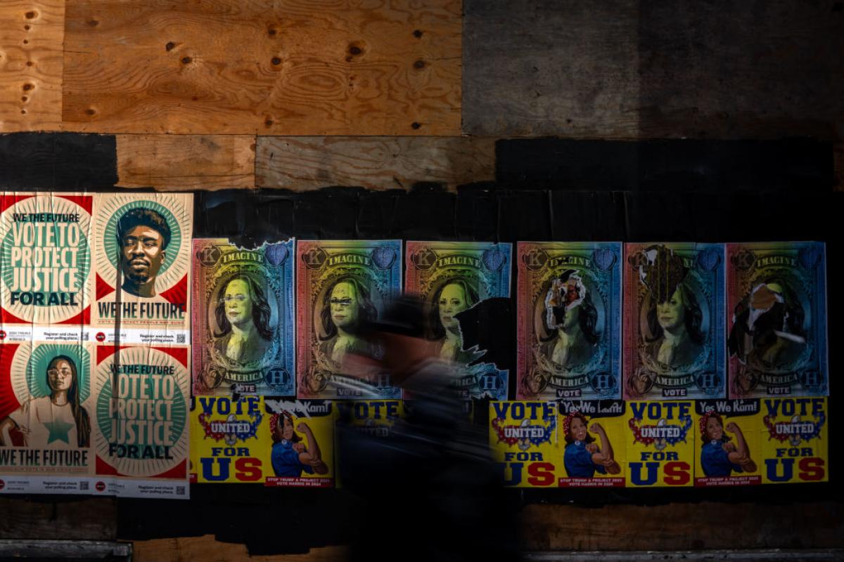 Un transeúnte pasa por delante de unos carteles electorales de Kamala Harris pegados en las paredes de un edificio de Pensilvania.