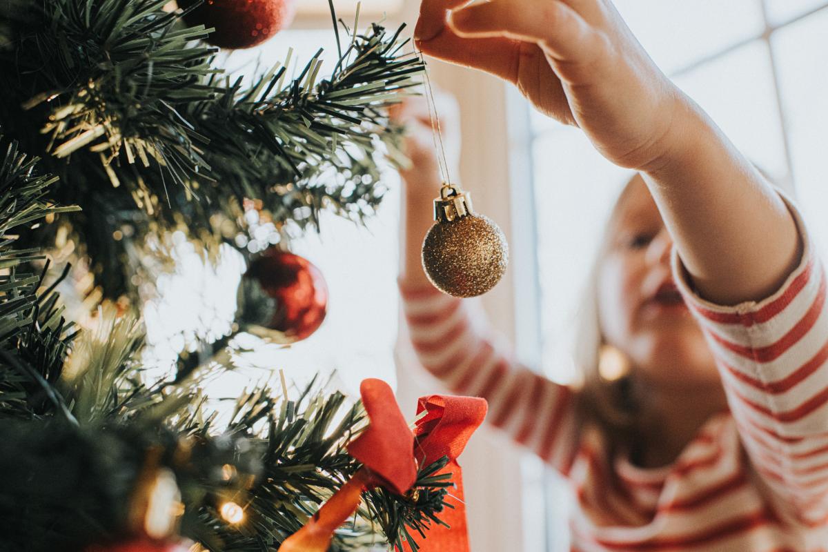 Una niña decorando un árbol de Navidad.