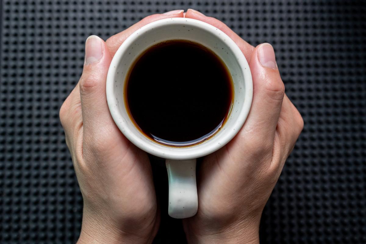 Una persona con una taza de café entre las manos.