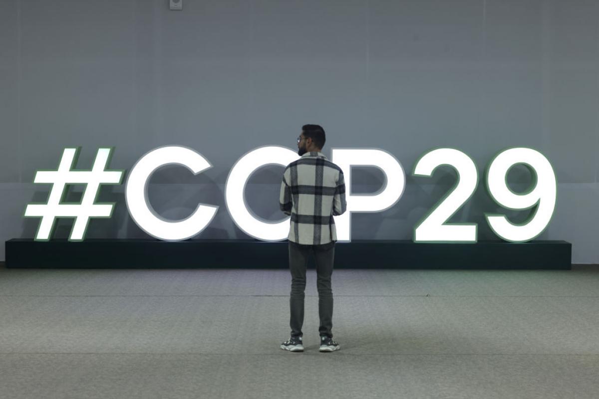 Un asistente a la COP29 de Bakú, ante una señal luminosa de la cumbre climática.