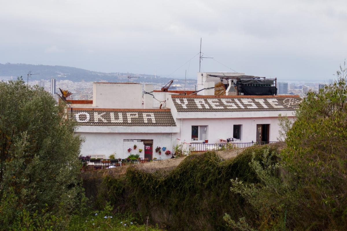 El popular grafiti 'Okupa y Resiste' que se puede ver en el tejado de una vivienda próxima al Parc Güell, en Barcelona.