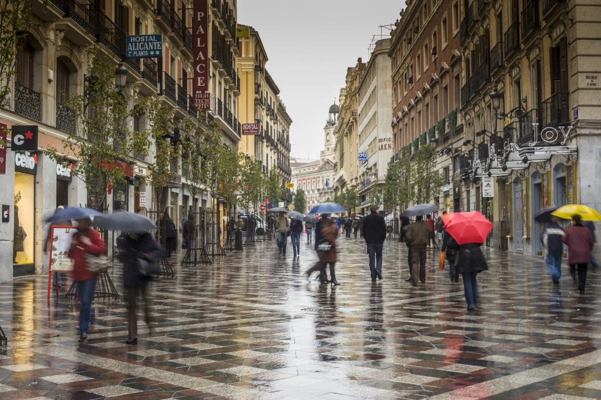 Transeúntes caminan bajo la lluvia en la Calle Arenal de Madrid.