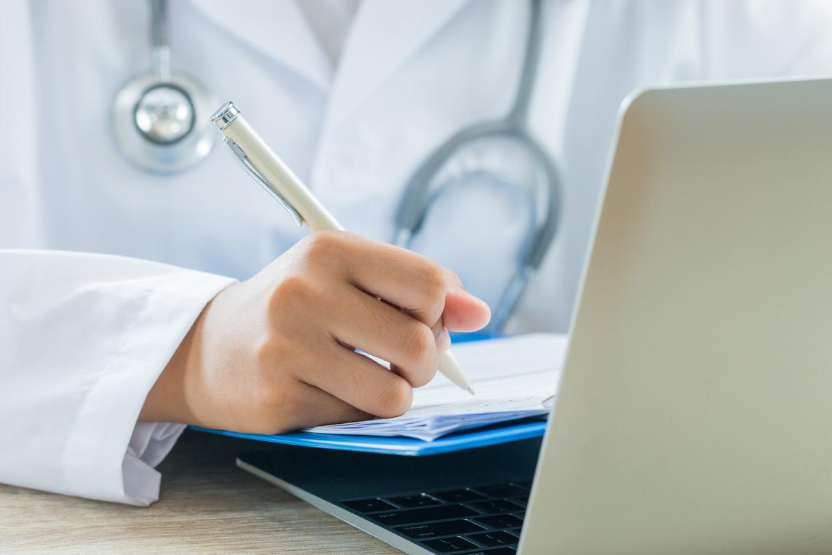 Una médico firma un certificado.