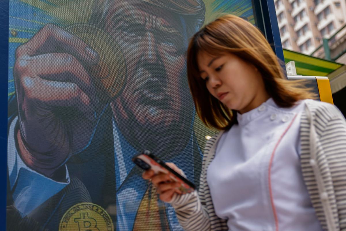 Una persona pasea junto a una ilustración del presidente reelecto Donald Trump, en Hong Kong.