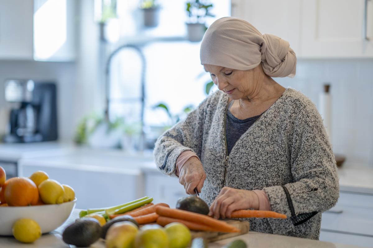 Una mujer pela y prepara verduras en la cocina.
