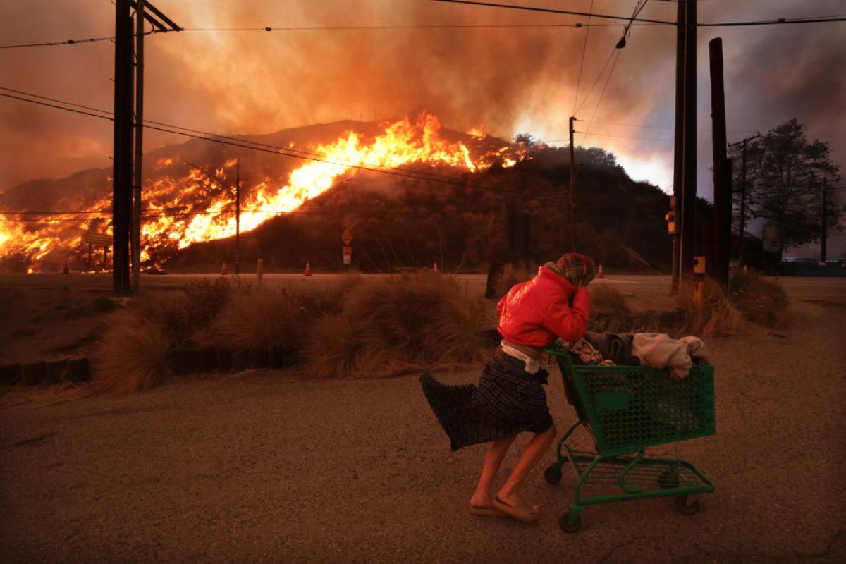 Una persona sin hogar tira de un carrito de supermercado huyendo de los incendios de Los Ángeles.