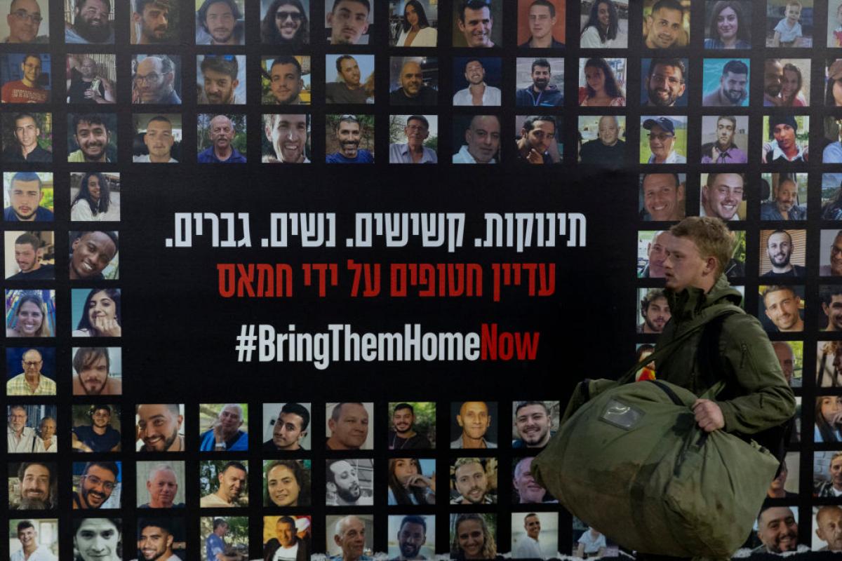 Un soldado pasa junto a un muro cubierto de fotos de rehenes israelíes retenidos por Hamás