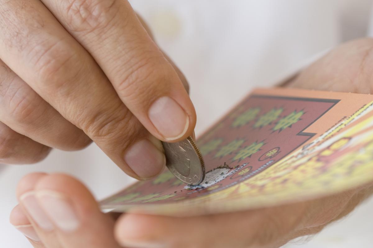 Un hombre rasca una tarjeta de lotería con una moneda