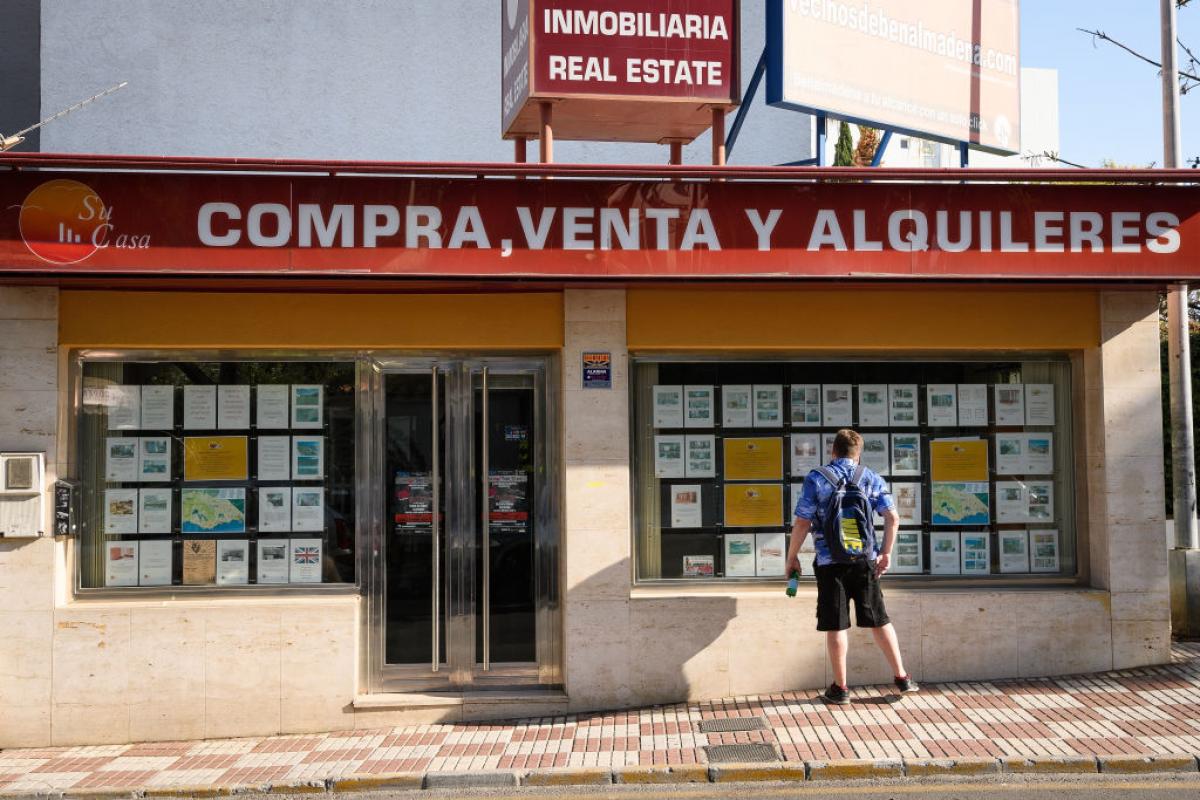 Un turista lee los anuncios de venta y alquiler de una inmobiliaria de Benalmádena.