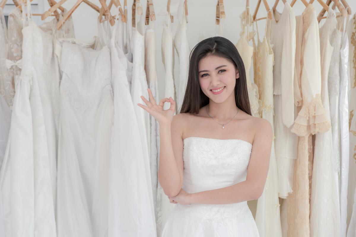 Imagen de una joven ante distintos vestidos de novia, en una tienda especializada de bodas.