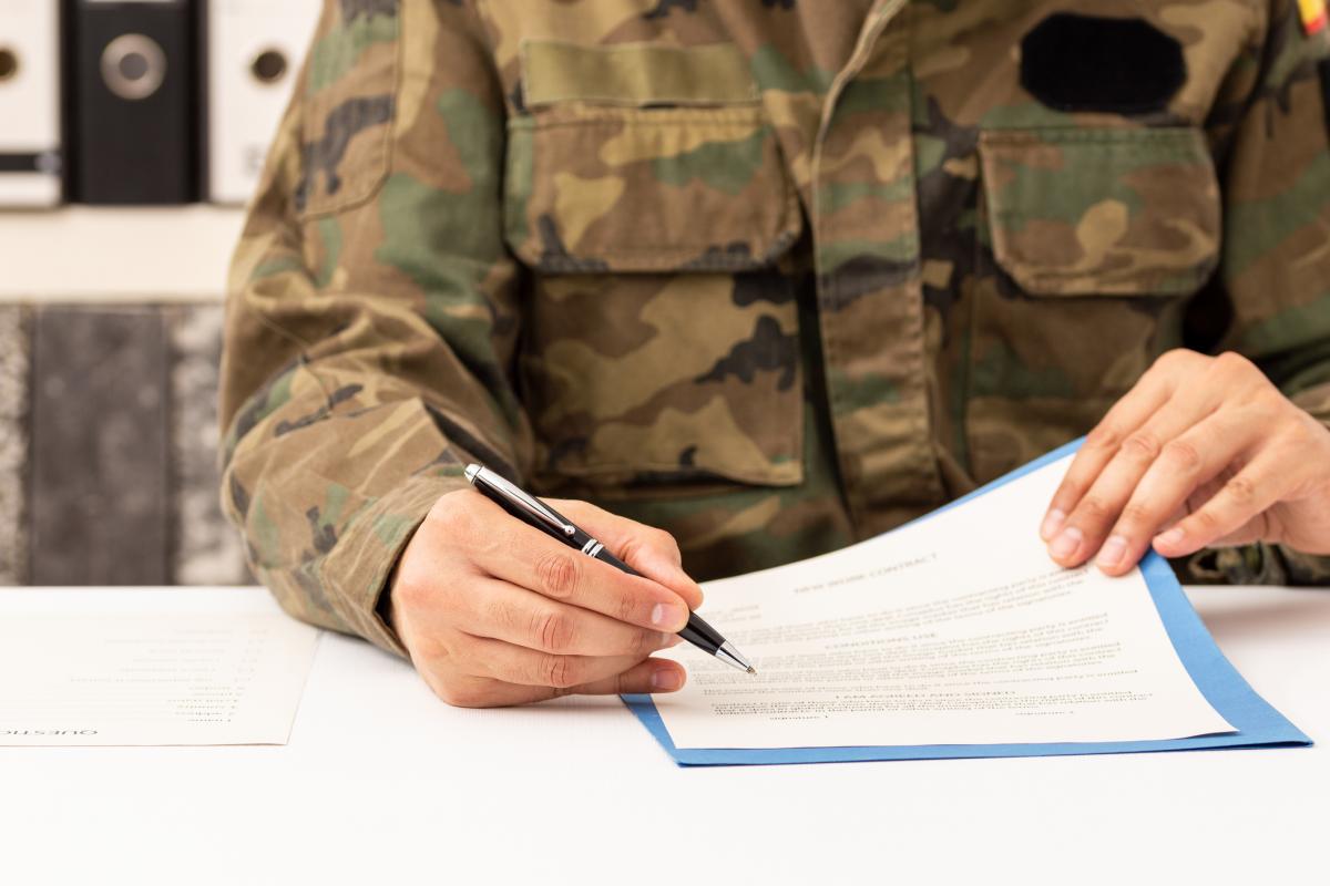 Un militar firma un contrato.