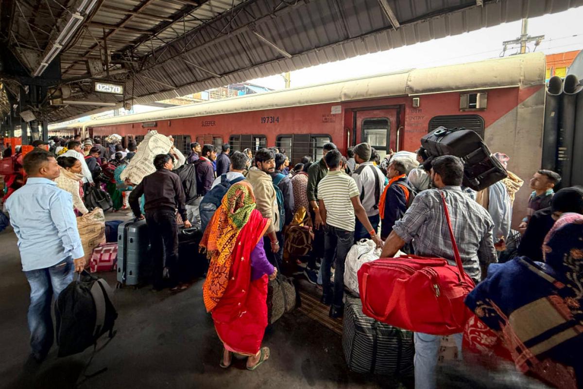 Un grupo de pasajeros intenta subirse a un tren en la estación de Nueva Delhi.