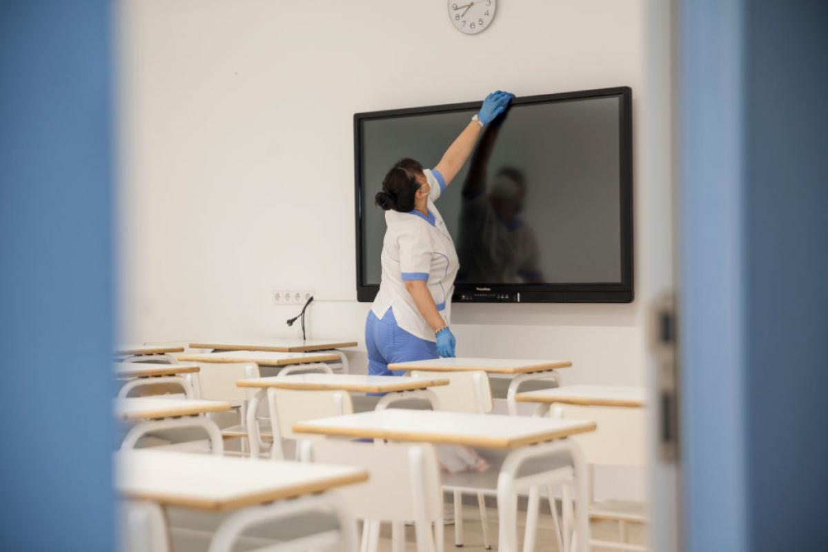 Una trabajadora de la limpieza desinfecta el aula de un colegio en España