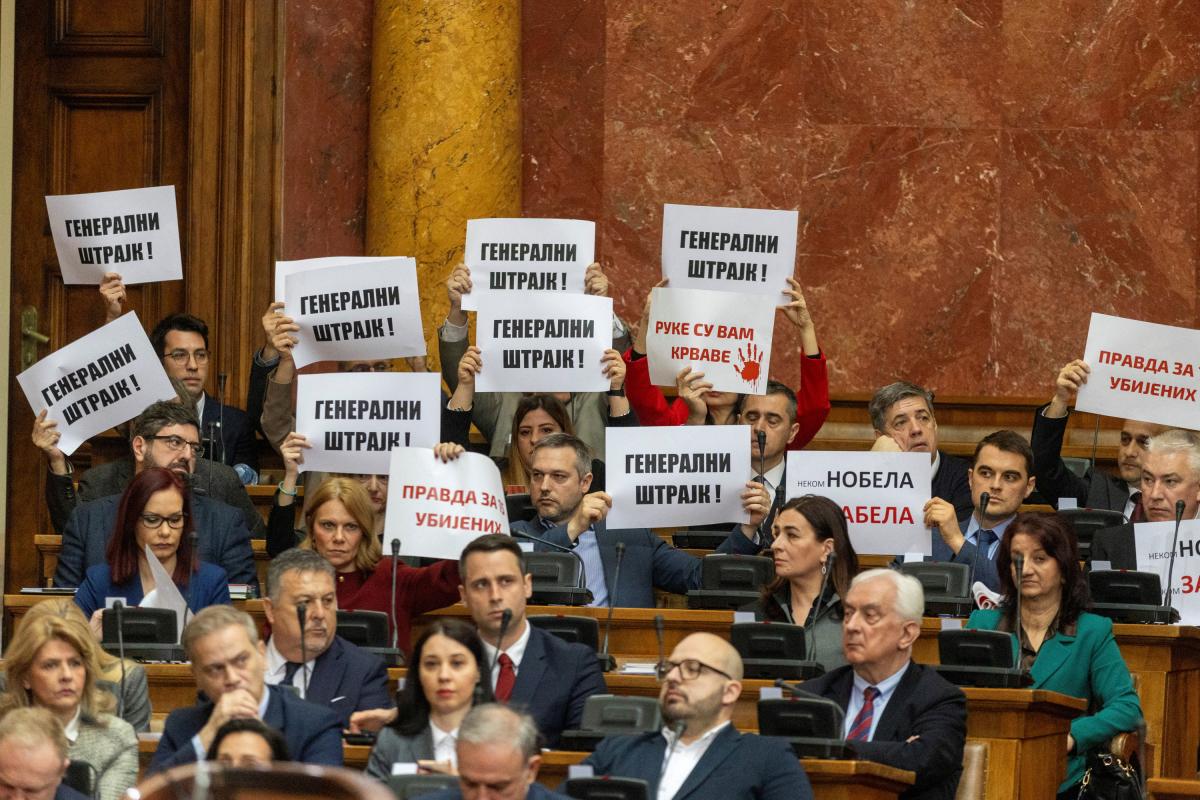 Integrantes de la oposición serbia muestran carteles reclamando un gobierno de transición.