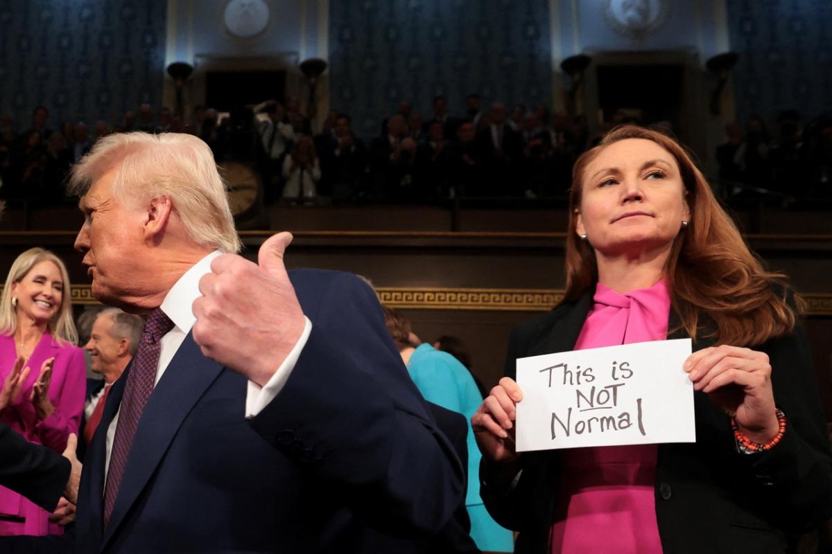 La senadora demócrata Melanie Stansbury, junto a Donald Trump, sostiene un cartel en el que se lee el mensaje: "Esto no es normal"