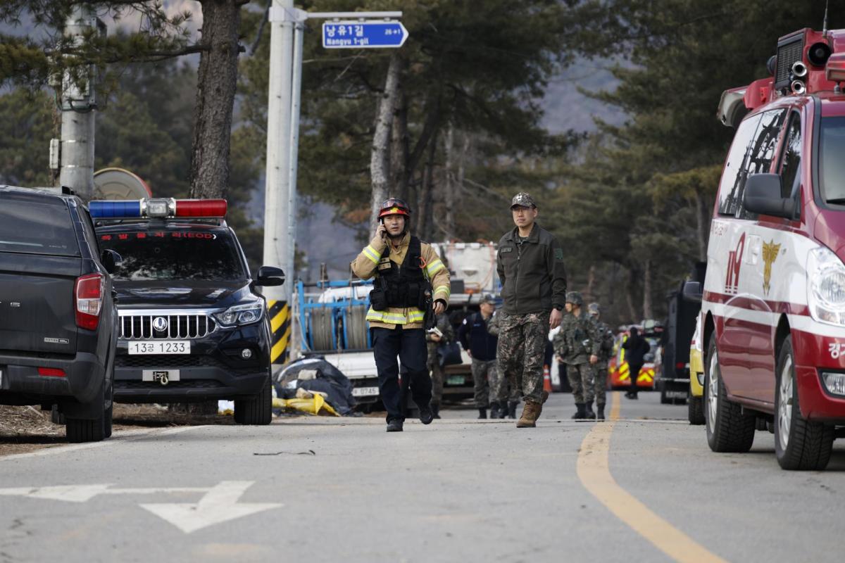 El personal de los servicios de rescate y los soldados caminan cerca del lugar del bombardeo accidental de un avión de combate, en Pocheon, Corea del Sur.