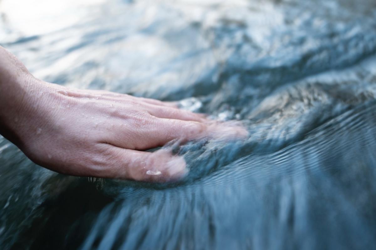La mano de una mujer agita el agua, provocando una serie de turbulencias.