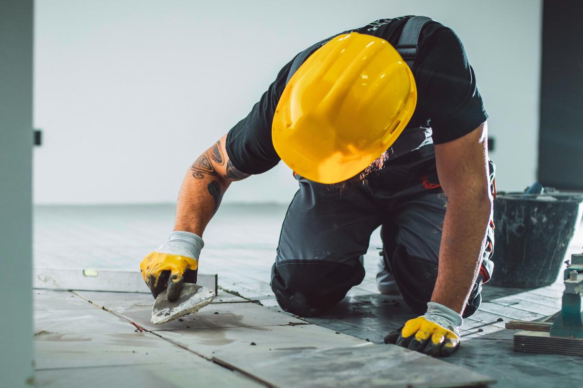 Imagen de un obrero alicatando baldosas.