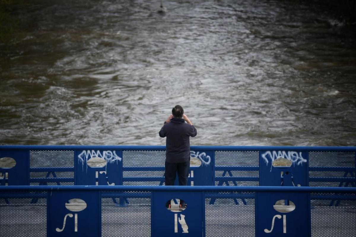 Una persona fotografía el curso del río de Manzanares, crecido por las intensas lluvia que trae la borrasca Martinho.