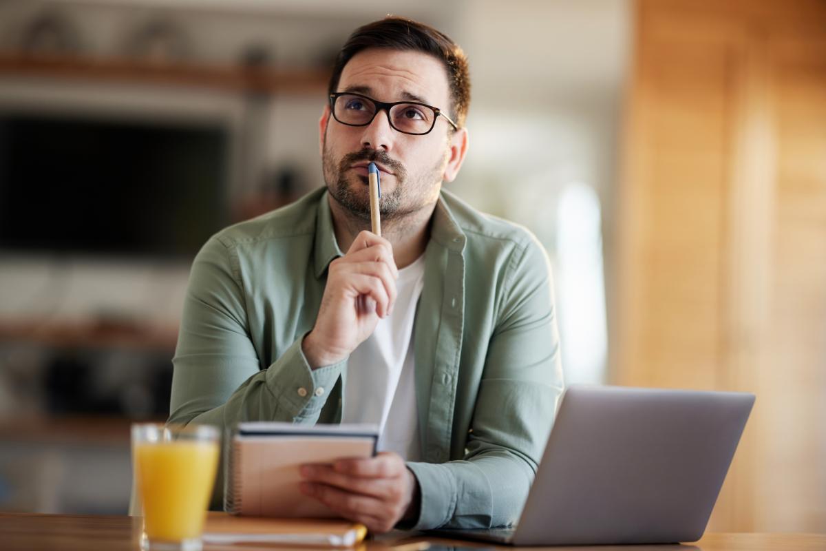 Un hombre pensativo escribiendo.
