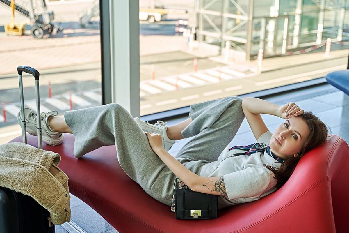 Una chica tirada en un sillón del aeropuerto descansando.