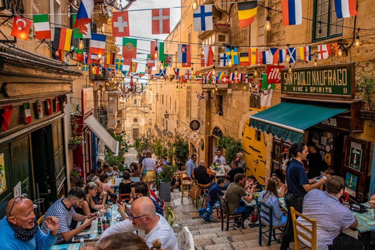 Un grupo de turistas come en un restaurante abierto en uno de los callejones de la capital de Malta, La Valeta.