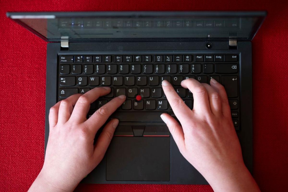 Una mujer que teletrabaja escribe en su portátil de empresa.