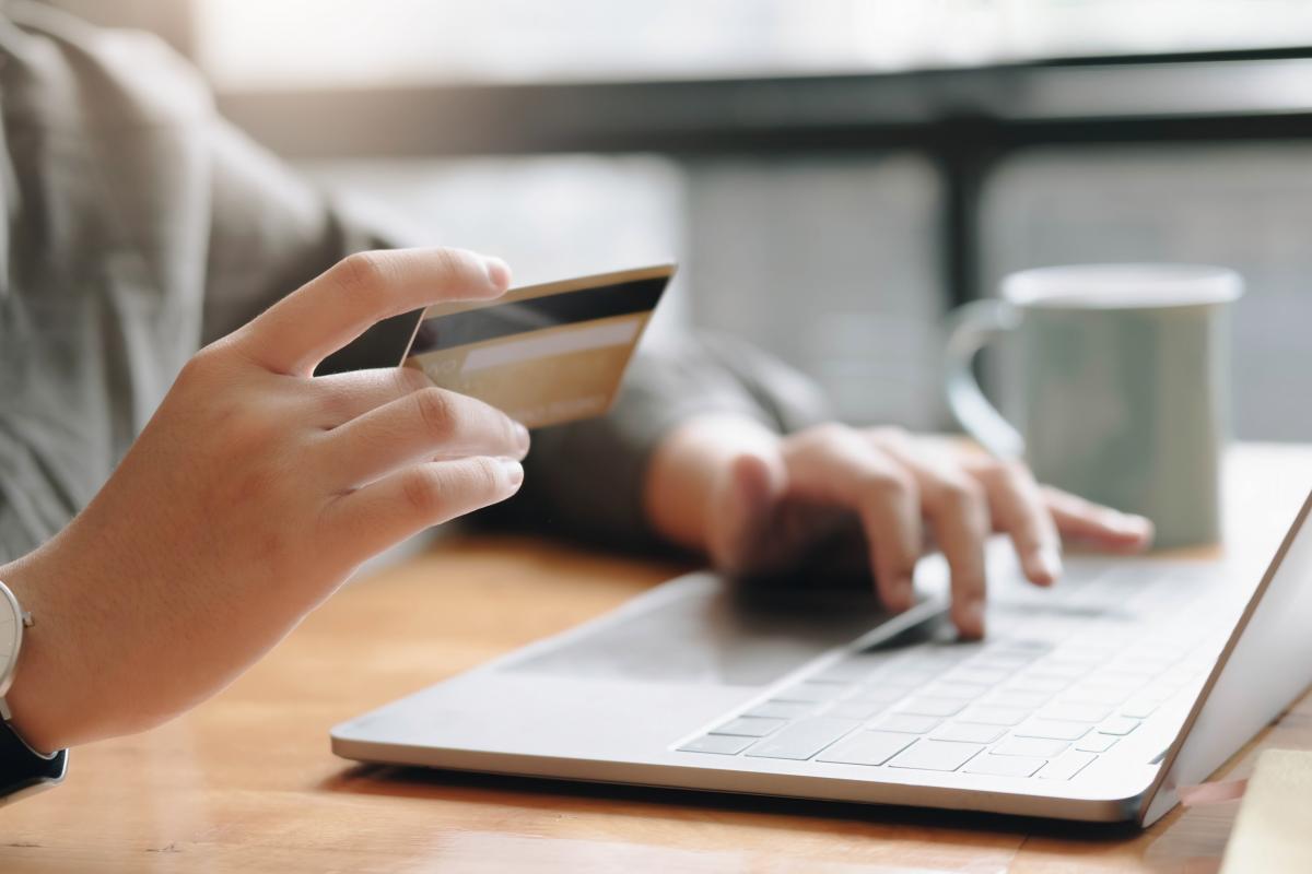 Una mujer frente al ordenador con una tarjeta de crédito.