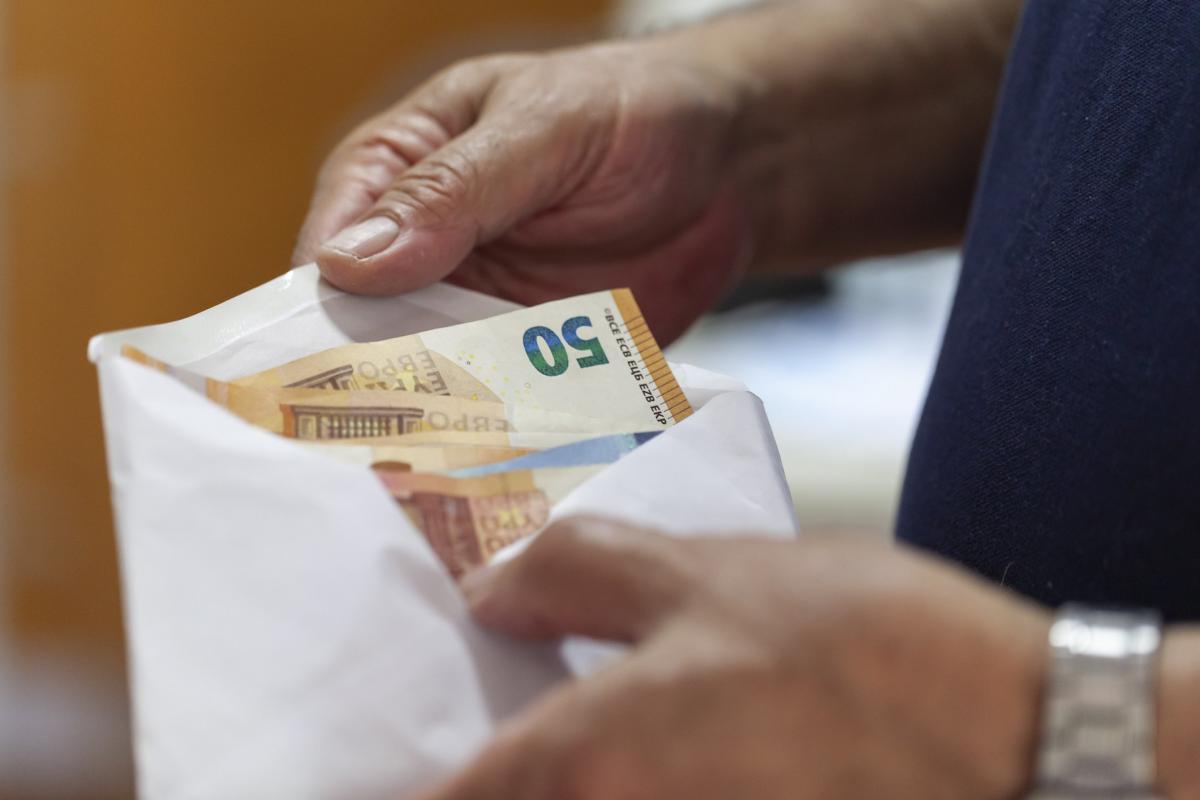“Manos de una persona mayor sosteniendo un sobre con billetes de euro, relacionado con el timo del tocomocho en Burgos”