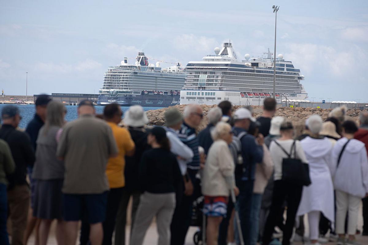 Turistas en el puerto de Palma, con varios cruceros al fondo.