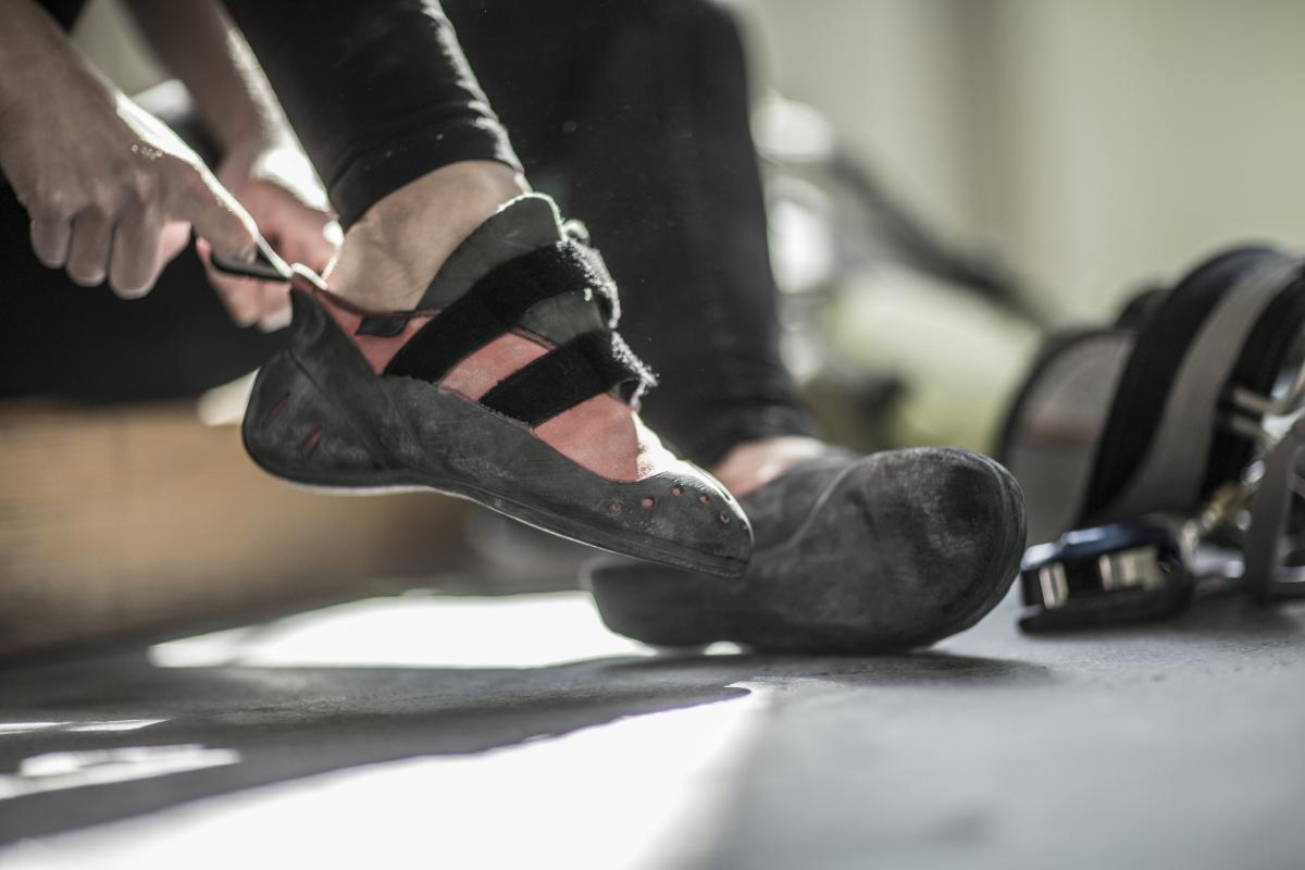 Una persona calzándose las zapatillas de escalada en el gimnasio