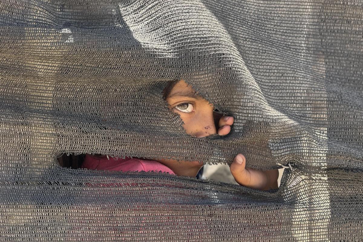 Una niña se asoma tras una tienda improvisada en el puerto en la Ciudad de Gaza.