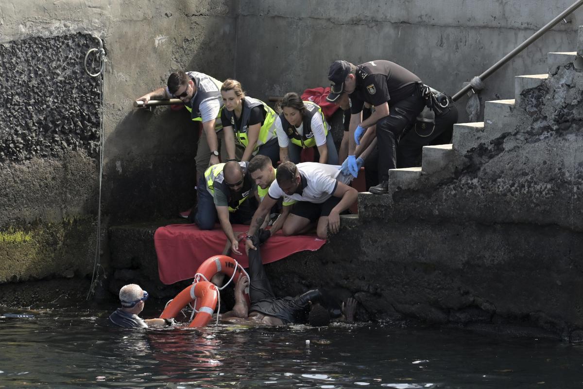 Personal de emergencias asiste a los ocupantes de un cayuco volcado en el puerto de La Restinga (El Hierro, Canarias), cuando iban a desembarcar.