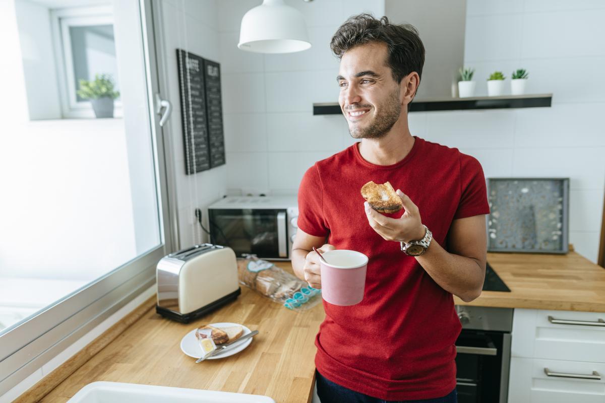 Un joven disfruta de se desayuno con un café y una tostada con mantequilla
