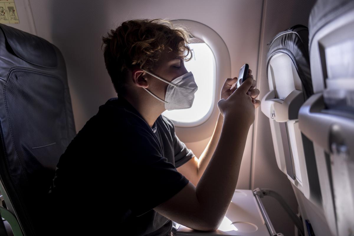 Imagen de archivo de un niño con mascarilla, viajando en avión.