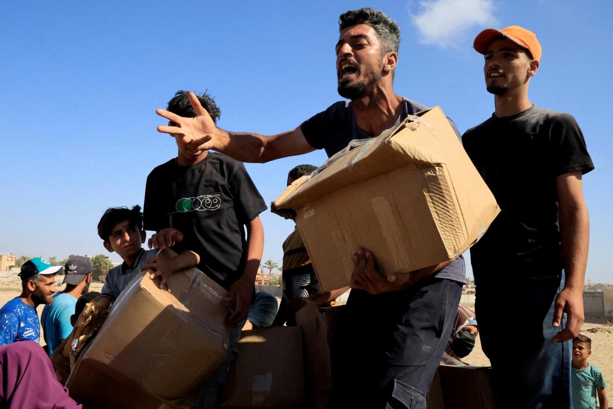 Palestinos tratando de conseguir algo de la ínfima ayuda humanitaria que llega a repartirse en un punto de distribución, en el paso de Rafá.