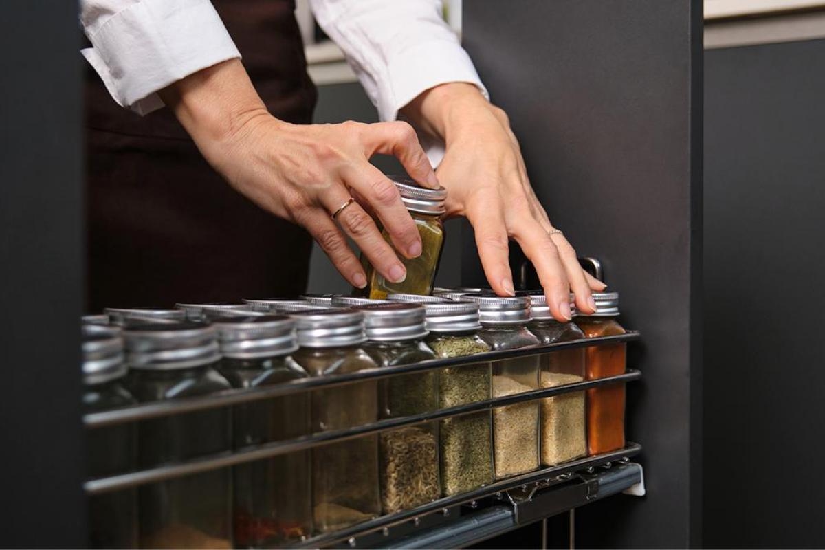 Unas manos cogiendo frascos de especias de un organizador.