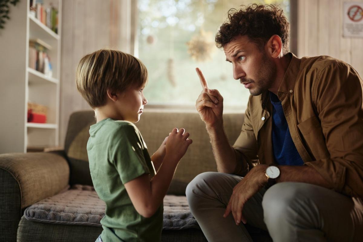 Un padre regaña a su hijo en la sala de estar.