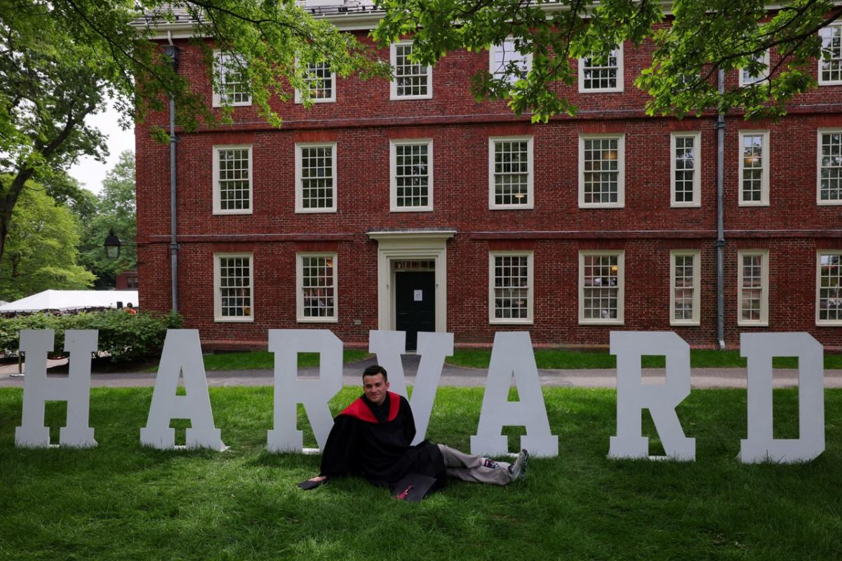Un estudiante de Harvard posa ante un cartel de la universidad estadounidense.