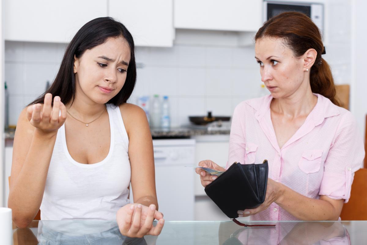 Imagen de archivo de una madre dando dinero a su hija adolescente.