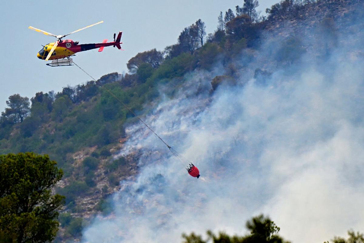 Un helicóptero trata de apagar las llamas del incendio en Paüls