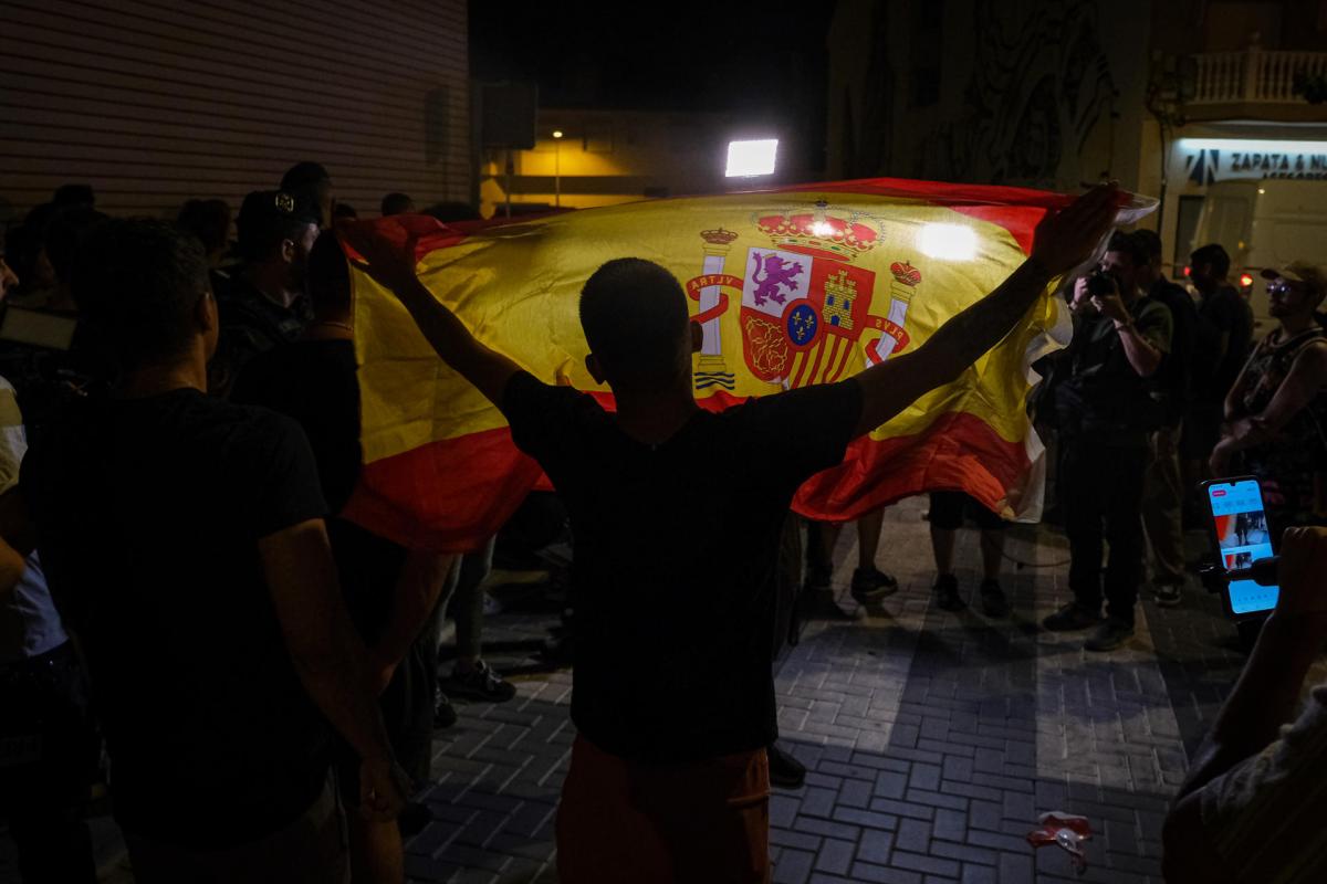 Un manifestante con una bandera de España mientras increpa a periodistas en Torre Pacheco