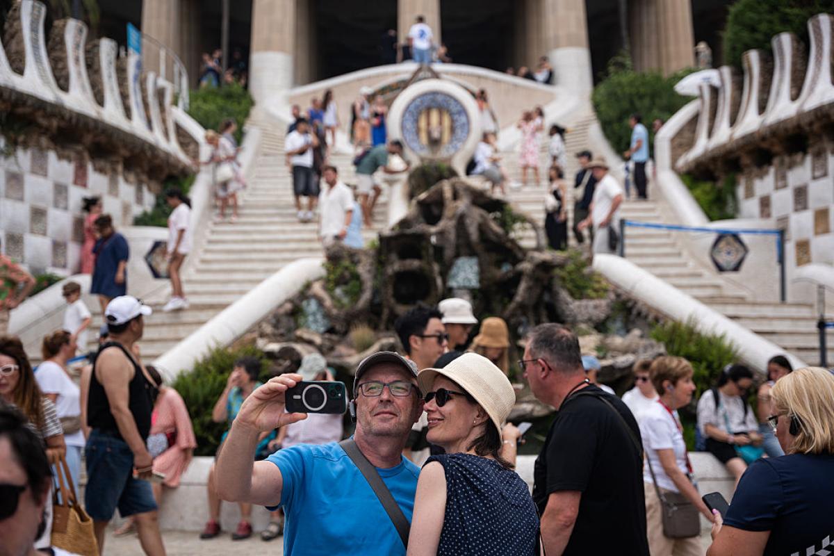 Turistas se fotografían en la escalera de entrada del Parc Güell, en Barcelona.