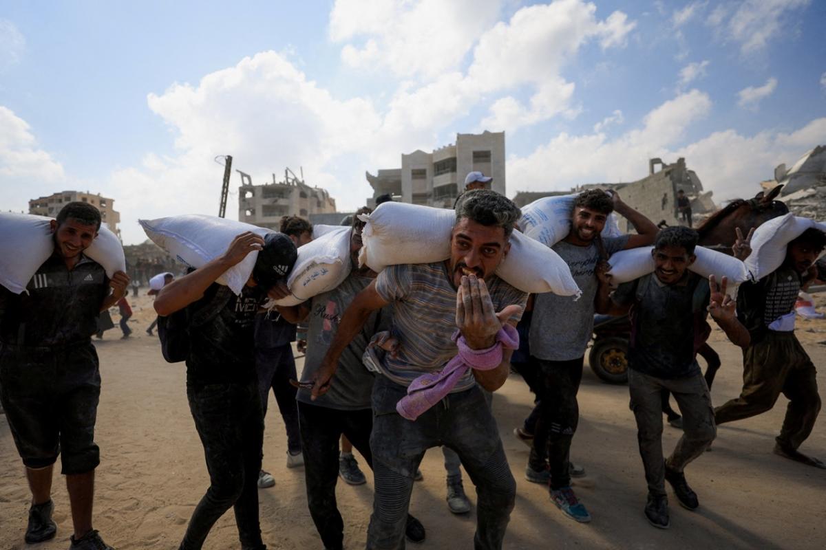 Un grupo de palestinos regresa a su campamento después de recoger ayudaen Beit Lahia.