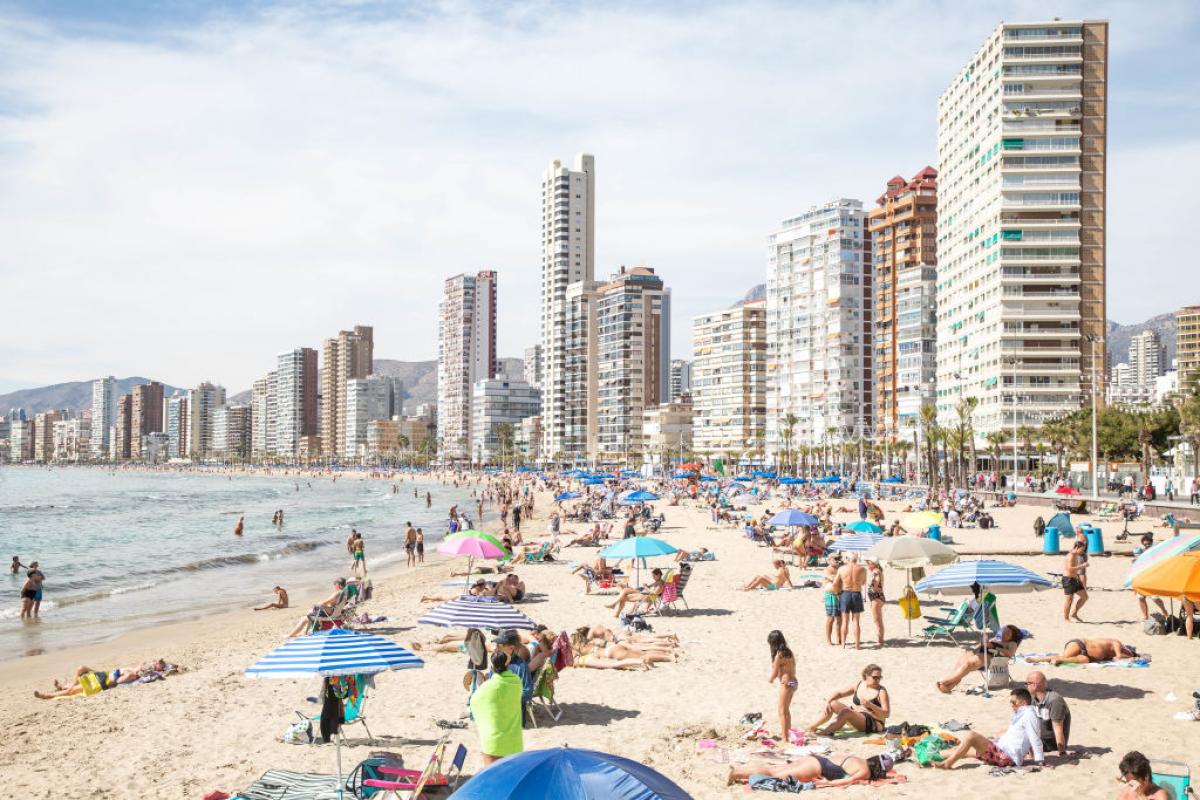 Turistas en la playa de Benidorm durante el verano. Mientras los destinos costeros se llenan, más de un tercio de los españoles no puede permitirse una semana de vacaciones, según el INE.