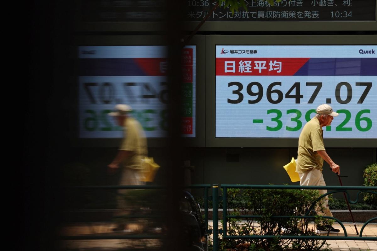 Un hombre pasa delante de una pantalla con las cotizaciones de las acciones del índice Nikkei, en la bolsa de Tokio.