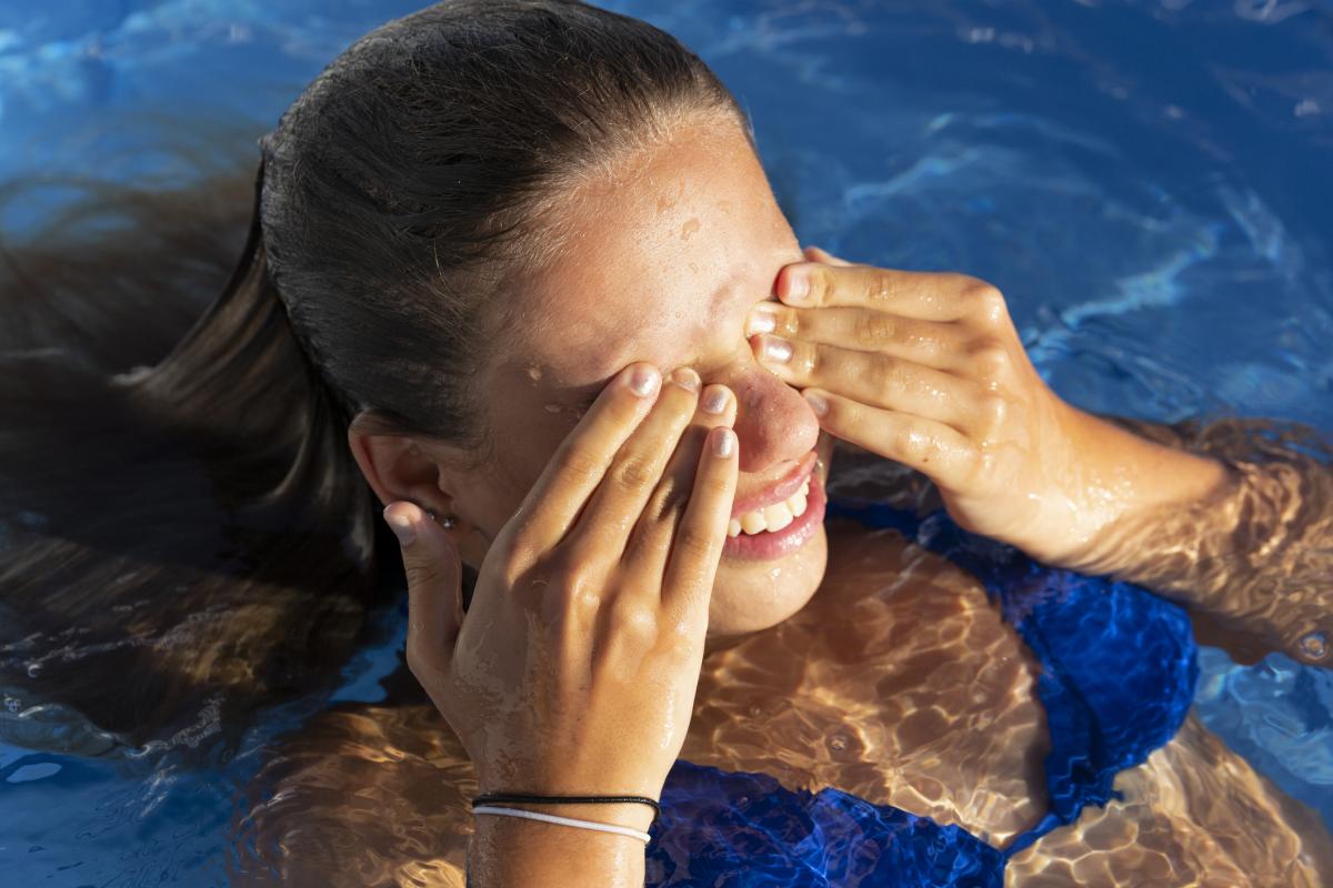 Imagen de archivo de una mujer frotándose los ojos en la piscina.