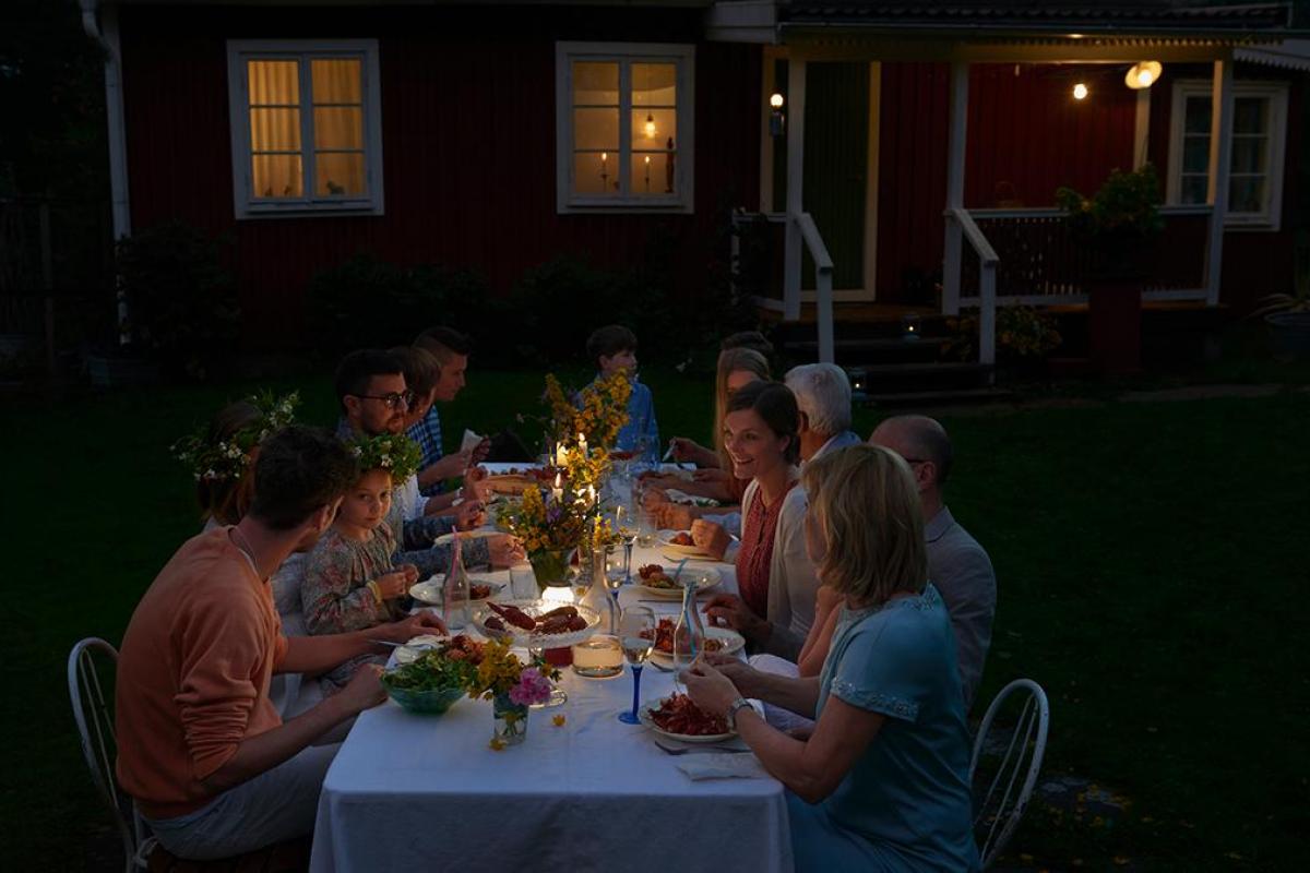 Una familia cenando en el jardín con unas lámparas en la mesa.