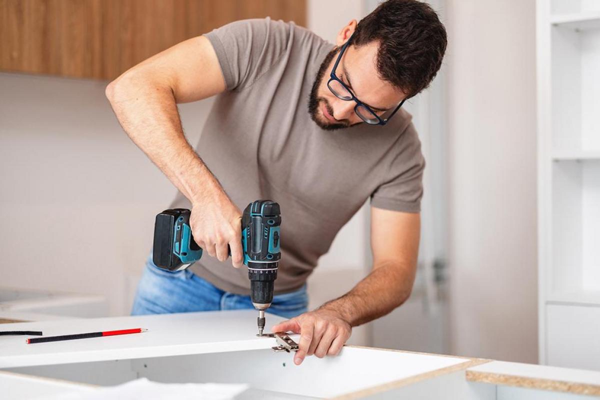 Un hombre taladrando una estantería.