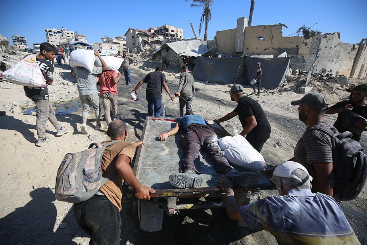 Un grupo de gazatíes traslada el cuerpo de un fallecido en las colas para pedir ayuda en Gaza.